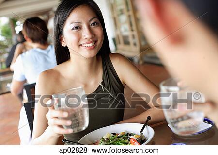 Stock Photo - Couple having a meal in restaurant, holding glasses of water . Fotosearch