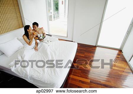 Couple having breakfast in bed, high angle view View Large Photo Image Stock Photo - Couple having breakfast in bed, high angle view . Fotosearch
