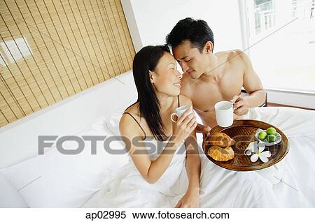 Couple having breakfast in bed, sitting face to face View Large Photo Image Stock Photography - Couple having breakfast in bed, sitting face to face . Fotosearch