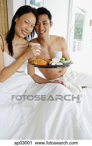 Couple having breakfast in bed, smiling at camera View Large Photo Image Stock Image - Couple having breakfast in bed, smiling at camera. Fotosearch
