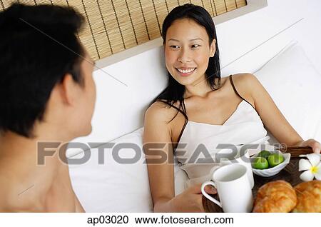 Stock Image - Couple in bed having breakfast . Fotosearch
