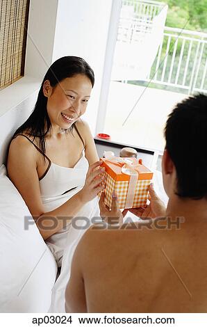 Couple in bed, man giving woman a gift View Large Photo Image Picture - Couple in bed, man giving woman a gift . Fotosearch