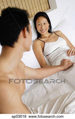 Stock Photo - Couple in bed, man holding womans hand . Fotosearch