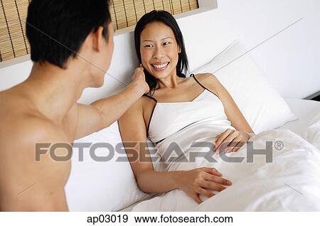 Couple in bed, man touching womans face View Large Photo Image Stock Photo - Couple in bed, man touching womans face. Fotosearch