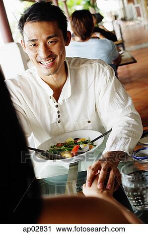 Couple in restaurant, holding hands across the table View Large Photo Image Stock Image - Couple in restaurant, holding hands across the table . Fotosearch