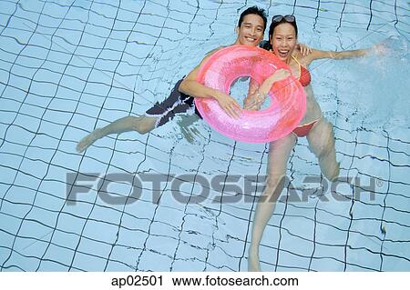 Couple in swimming pool holding on to inflatable ring View Large Photo Image Stock Image - Couple in swimming pool holding on to inflatable ring . Fotosearch