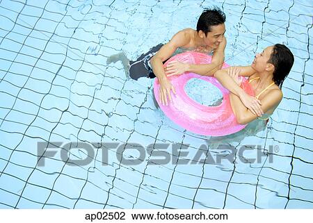 Couple in swimming pool leaning on inflatable ring View Large Photo Image Stock Image - Couple in swimming pool leaning on inflatable ring . Fotosearch