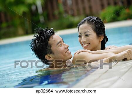 Couple in swimming pool, smiling at each other View Large Photo Image Picture - Couple in swimming pool, smiling at each other . Fotosearch