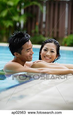 Stock Image - Couple in swimming pool, smiling. Fotosearch