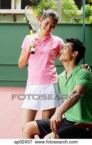 Stock Photo - Couple in tennis outfit, smiling at each other . Fotosearch