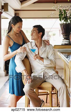 Stock Photography - Couple next to bar counter, man sitting, woman standing next to him . Fotosearch