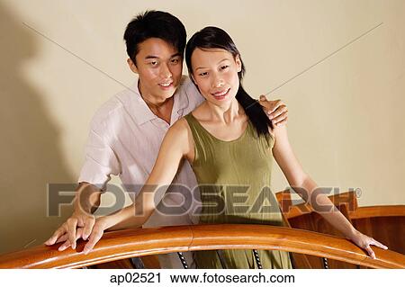 Stock Image - Couple on staircase, smiling at camera, portrait . Fotosearch