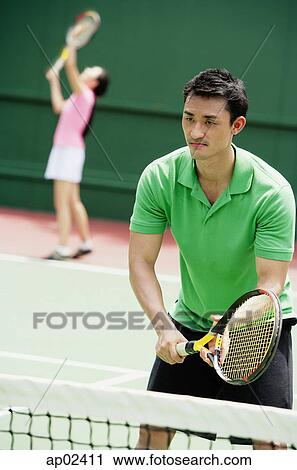 Stock Image - Couple playing tennis, mixed doubles . Fotosearch