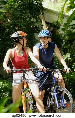Couple riding bikes and smiling, looking at each other View Large Photo Image Stock Photograph - Couple riding bikes and smiling, looking at each other . Fotosearch