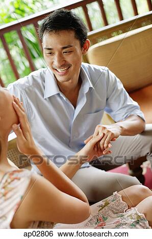 Couple sitting face to face, holding hands, woman with hand on face View Large Photo Image Stock Photograph - Couple sitting face to face, holding hands, woman with hand on face . Fotosearch