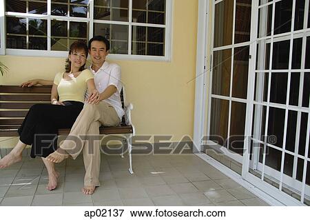 Couple sitting on bench in patio, holding hands View Large Photo Image Stock Photo - Couple sitting on bench in patio, holding hands . Fotosearch