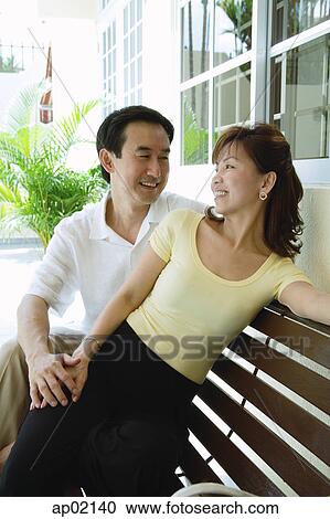 Couple sitting on bench looking at each other View Large Photo Image Stock Image - Couple sitting on bench looking at each other . Fotosearch