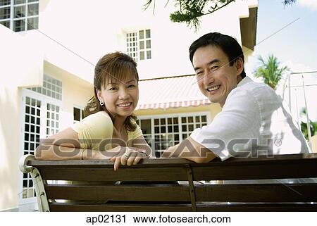 Couple sitting on bench, smiling at camera View Large Photo Image Stock Image - Couple sitting on bench, smiling at camera . Fotosearch