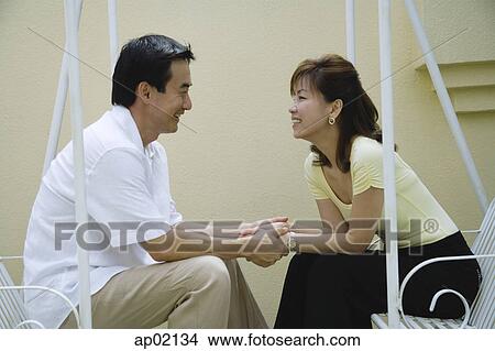 Couple sitting on swing, looking at each other View Large Photo Image Picture - Couple sitting on swing, looking at each other . Fotosearch