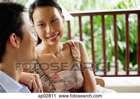 Couple sitting side by side, smiling at each other View Large Photo Image Stock Image - Couple sitting side by side, smiling at each other . Fotosearch
