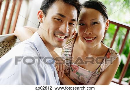 Couple sitting side by side, smiling at camera View Large Photo Image Stock Image - Couple sitting side by side, smiling at camera . Fotosearch
