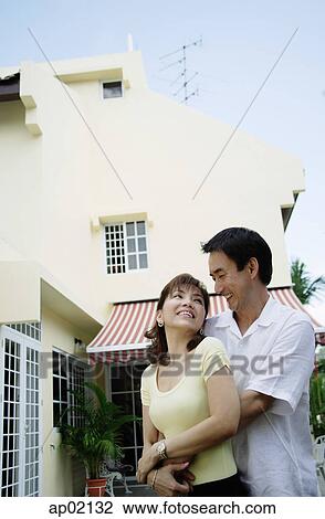 Couple standing in front of house, embracing View Large Photo Image Stock Image - Couple standing in front of house, embracing . Fotosearch