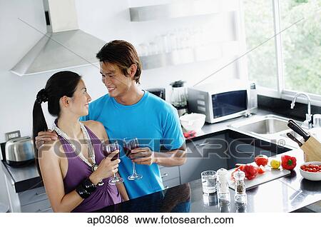 Couple standing in kitchen, holding wine glasses View Large Photo Image Stock Photo - Couple standing in kitchen, holding wine glasses . Fotosearch