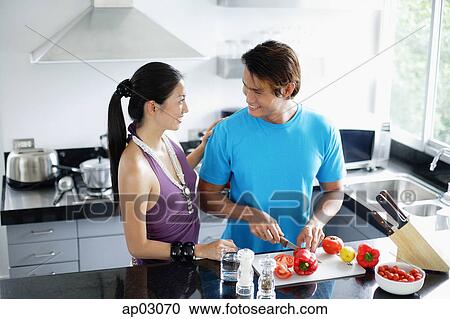 Couple standing in kitchen, man chopping vegetables View Large Photo Image Stock Image - Couple standing in kitchen, man chopping vegetables. Fotosearch