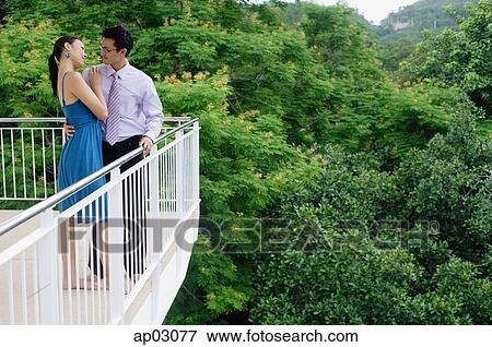 Stock Photo - Couple standing on balcony, embracing . Fotosearch