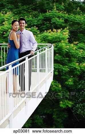 Couple standing on balcony, looking at camera View Large Photo Image Stock Image - Couple standing on balcony, looking at camera . Fotosearch
