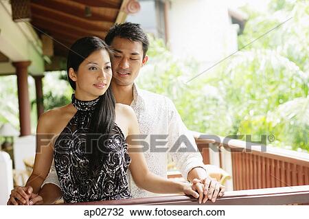 Couple standing together next to railing, man behind woman View Large Photo Image Stock Image - Couple standing together next to railing, man behind woman . Fotosearch