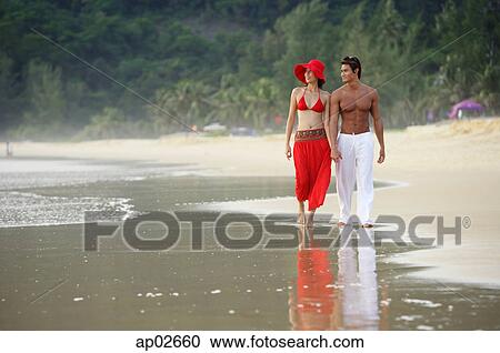 Couple walking along beach, holding hands View Large Photo Image Stock Image - Couple walking along beach, holding hands . Fotosearch
