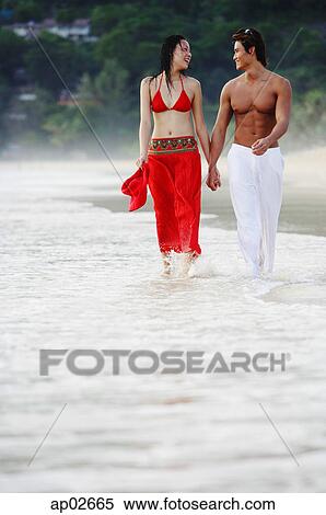 Couple walking, holding hands, along beach View Large Photo Image Stock Photography - Couple walking, holding hands, along beach . Fotosearch