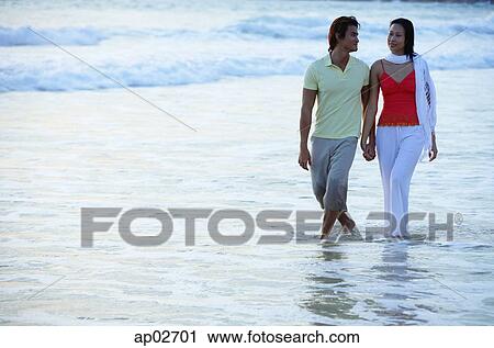 Couple walking on beach, ankle deep in water, holding hands View Large Photo Image Stock Image - Couple walking on beach, ankle deep in water, holding hands . Fotosearch