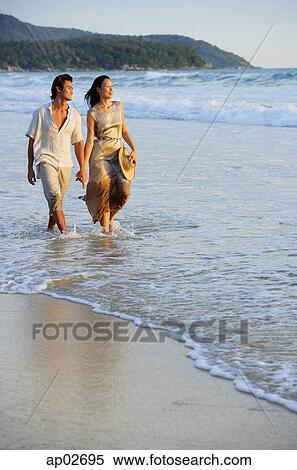 Couple walking on beach, looking away View Large Photo Image Stock Photography - Couple walking on beach, looking away . Fotosearch