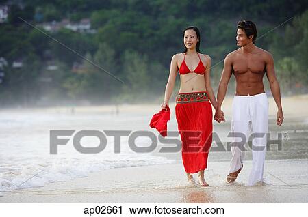 Couple walking side by side along beach, holding hands View Large Photo Image Stock Image - Couple walking side by side along beach, holding hands . Fotosearch