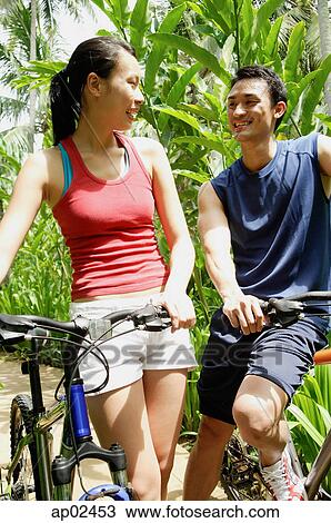Couple with bikes, smiling at each other View Large Photo Image Stock Image - Couple with bikes, smiling at each other . Fotosearch