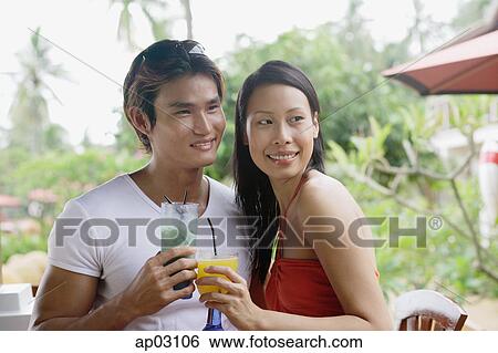 Stock Photograph - Couple with drinks, looking away, portrait . Fotosearch