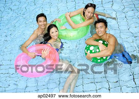 Couples in swimming pool with floats looking at camera View Large Photo Image Stock Photo - Couples in swimming pool with floats looking at camera . Fotosearch