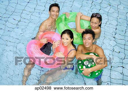 Stock Photo - Couples in swimming pool with floats . Fotosearch