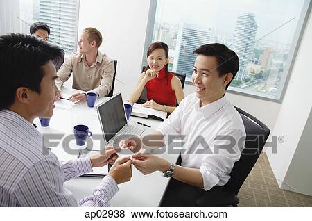 Executives around conference table, two businessmen exchanging business cards View Large Photo Image Stock Photo - Executives around conference table, two businessmen exchanging business cards . Fotosearch