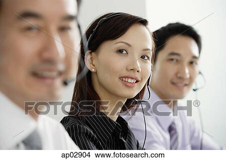 Executives in a row, wearing headsets, smiling at camera View Large Photo Image Picture - Executives in a row, wearing headsets, smiling at camera . Fotosearch