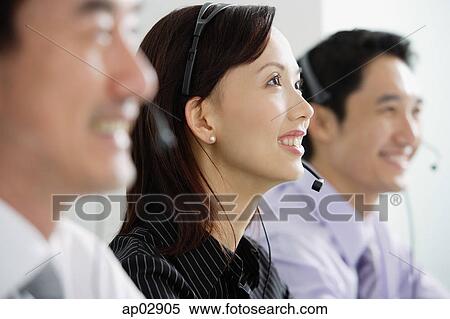 Stock Photography - Executives in a row, wearing headsets, looking away . Fotosearch