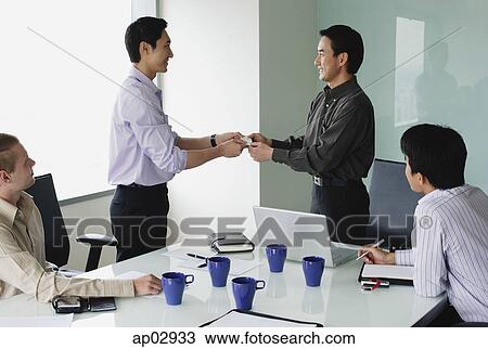 Executives in meeting room, exchanging business cards View Large Photo Image Stock Image - Executives in meeting room, exchanging business cards . Fotosearch