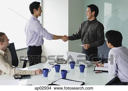 Executives in meeting room, shaking hands View Large Photo Image Picture - Executives in meeting room, shaking hands . Fotosearch
