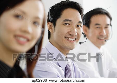 Stock Photograph - Executives wearing headsets, smiling at camera . Fotosearch