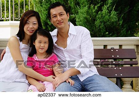 Family with one child, sitting on bench, looking at camera View Large Photo Image Stock Photo - Family with one child, sitting on bench, looking at camera. Fotosearch