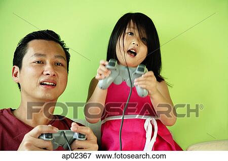 Father and daughter, side by side, playing video games View Large Photo Image Stock Photo - Father and daughter, side by side, playing video games. Fotosearch