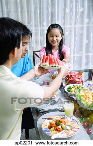 Father passing food to daughter at dining table View Large Photo Image Stock Image - Father passing food to daughter at dining table . Fotosearch