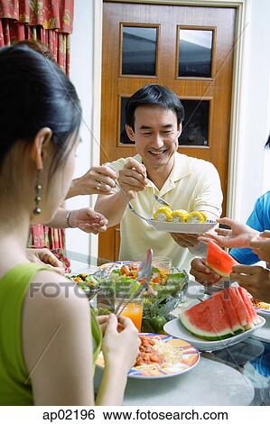 Father passing food to family members View Large Photo Image Stock Photograph - Father passing food to family members . Fotosearch
